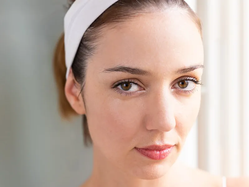 Retrato de mulher com faixa branca no cabelo, pele sem maquiagem